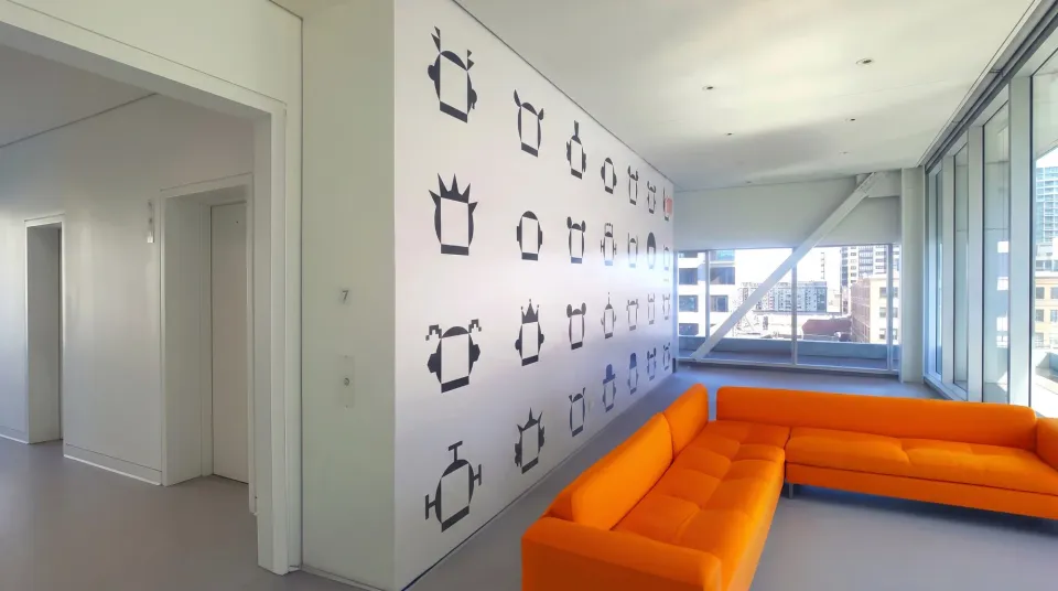 Office lobby wall with black cut-vinyl character graphics above an orange sofa, installed by CL Visual