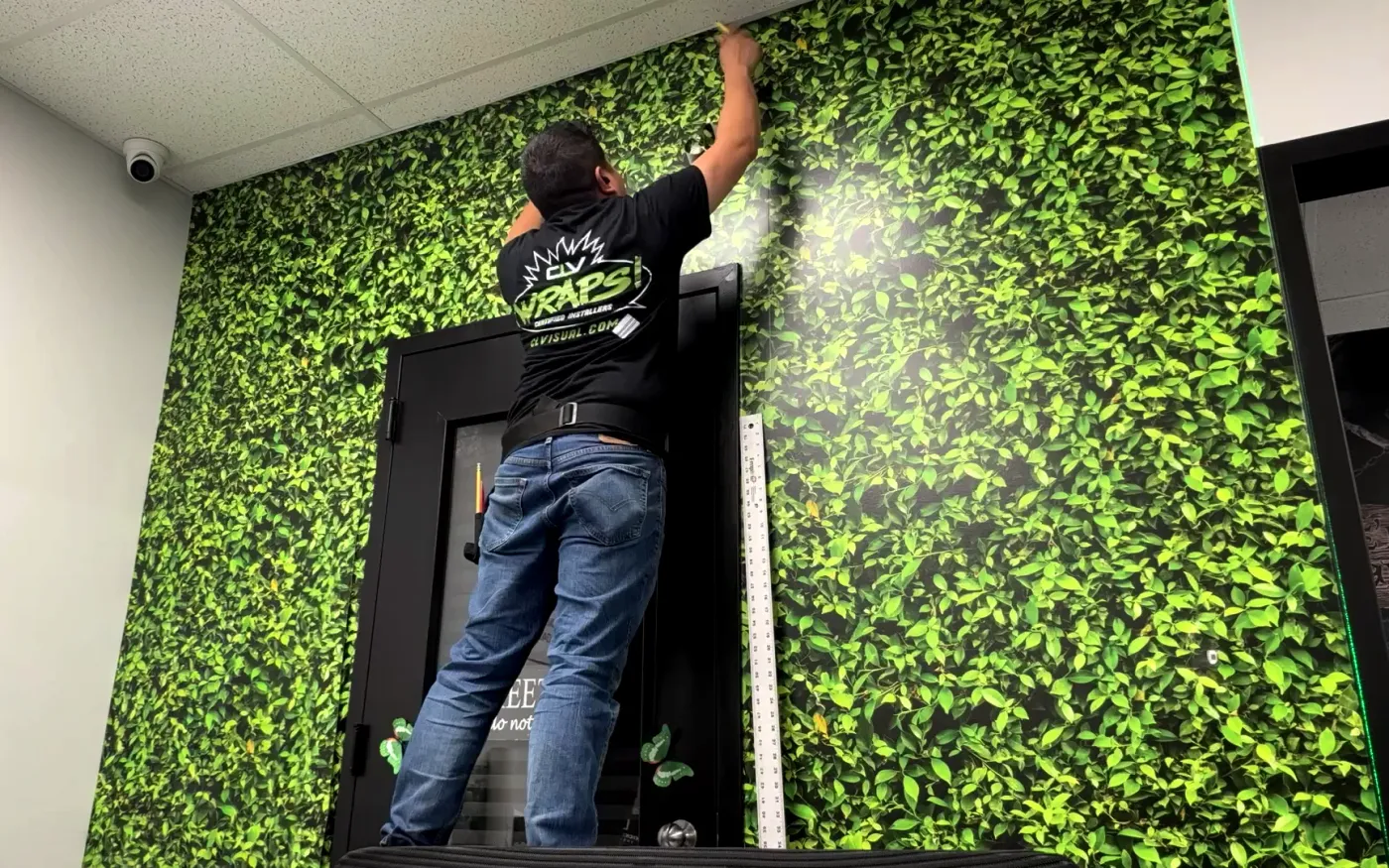 CL Visual installer applying a leafy green wall wrap