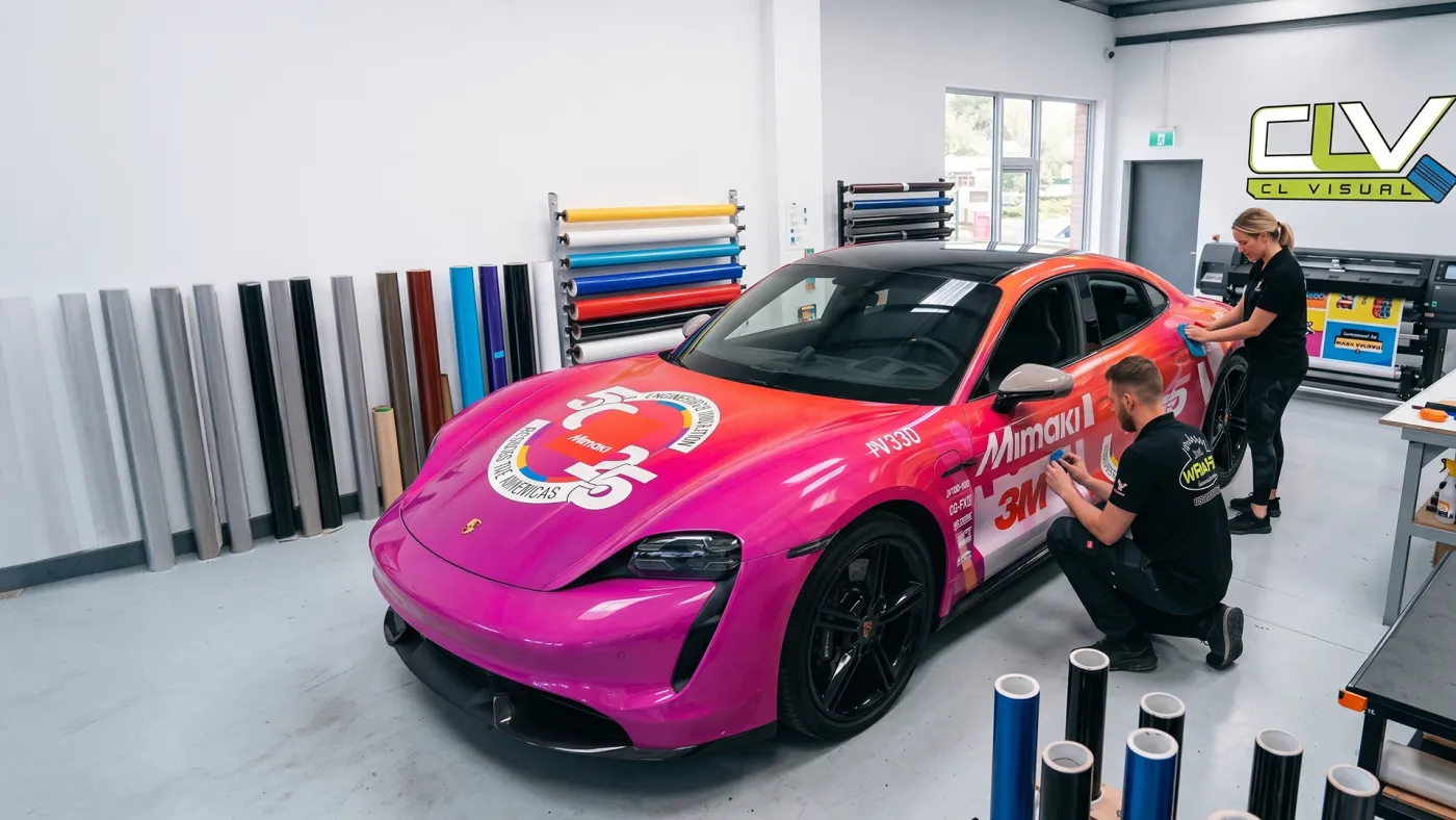 CL Visual installers finishing a pink and orange race-livery Porsche wrap in the shop