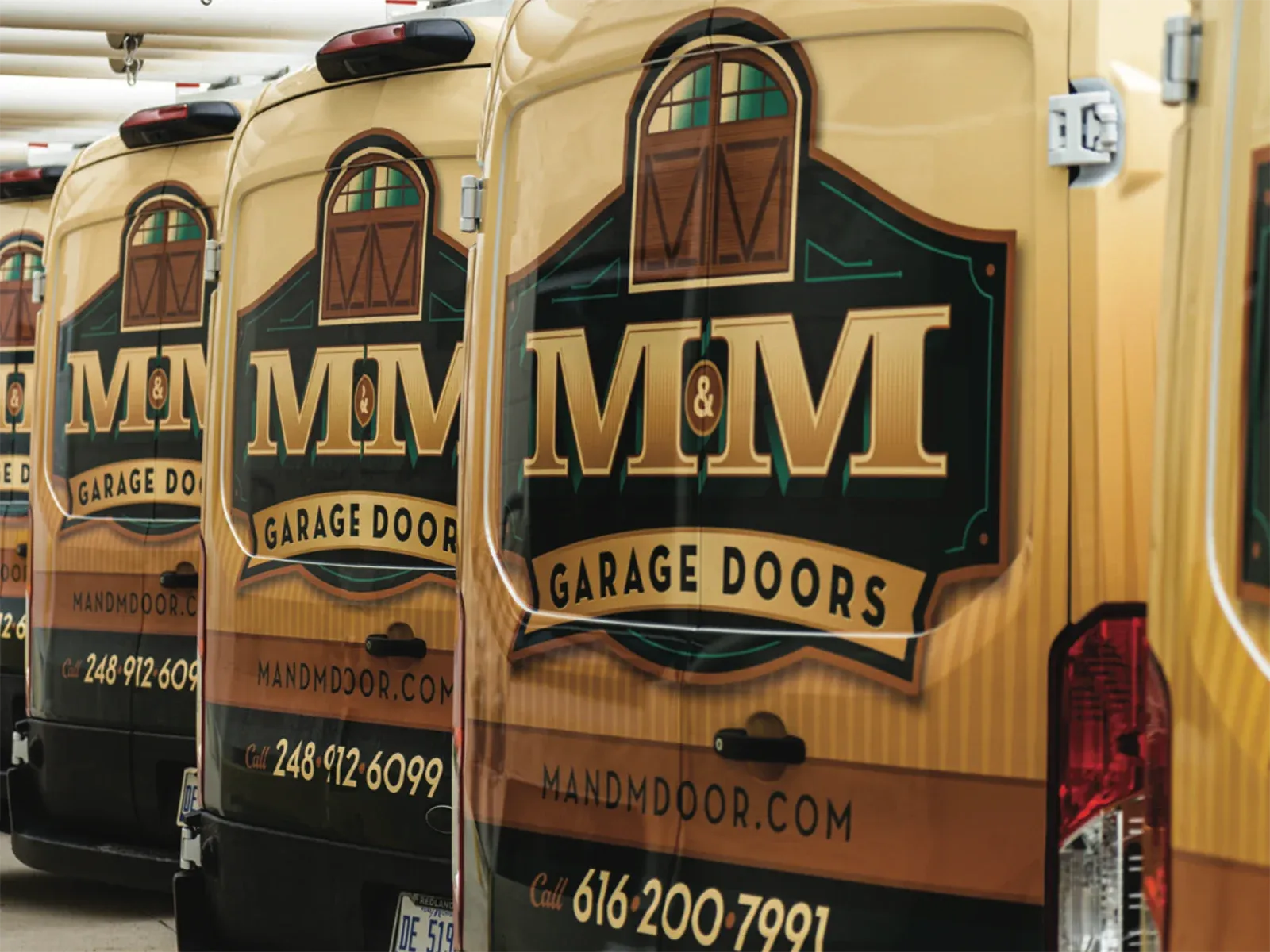 M&M Garage Doors fleet of wrapped vans lined up, managed through IDMyFleet