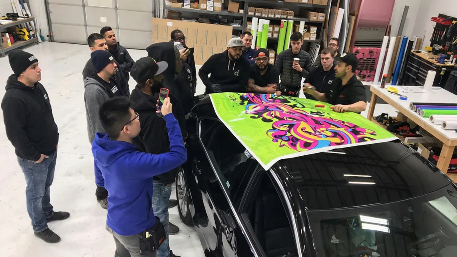CL Visual installers gathered around a car roof wrap in the install bay