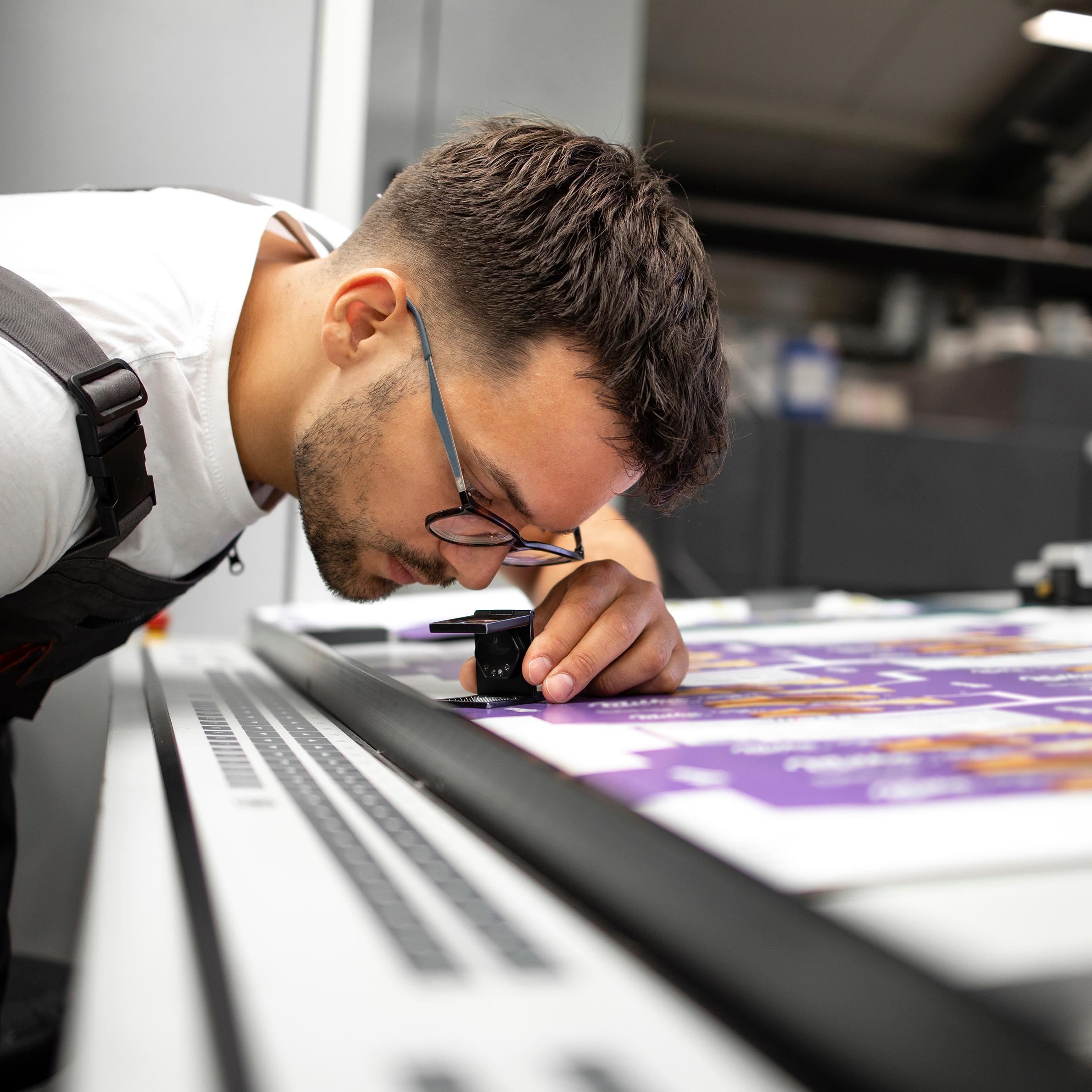 Worker checking print quality of graphics in modern printing house.